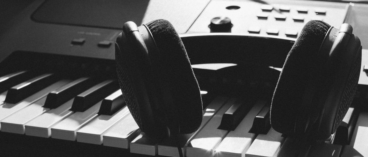 Close-up of headphones resting on piano keys, capturing the essence of music creation.